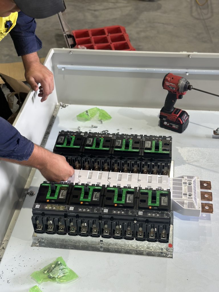 Preventive electrical maintenance work on a switchboard with circuit breakers being inspected and serviced